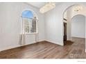 Bright living room with hardwood floors, chandelier, and a large arched window at 232 Elizabeth Ct, Fort Lupton, CO 80621