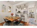 An elegant dining room with modern lighting, a dining table, and a breakfast bar overlooking the kitchen at 7841 W 55Th Ave, Arvada, CO 80002