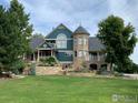 Beautiful home exterior with a turret, well-manicured landscaping, and a lush green lawn at 8400 Middle Fork Rd, Boulder, CO 80302