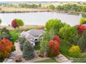 Stunning aerial view of a large home with mature trees near a tranquil lake, showcasing a peaceful setting at 10667 E Goose Haven Dr, Lafayette, CO 80026