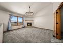 Spacious living room featuring plush carpet, a cozy fireplace, large windows, and bright natural light at 11837 County Road 39, Fort Lupton, CO 80621