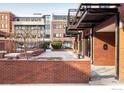 Exterior view of the red brick building featuring an outdoor patio space and professional landscaping at 1360 Walnut St # 204, Boulder, CO 80302