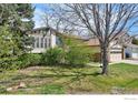 Front yard with mature trees, shrubs, and a two car attached garage at 1460 Harvard St, Longmont, CO 80503