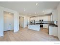 Open concept kitchen with white cabinetry, stone countertops, stainless appliances and hardwood floors at 170 Fremont Ct, Brighton, CO 80601