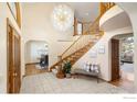 Elegant foyer featuring a grand staircase, chandelier, and tile flooring at 2245 Ridgeview Way, Longmont, CO 80504