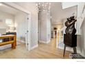 Open-concept entryway with modern chandelier, light wood floors, and an elegant sculpture at 6334 N Dayton Way, Denver, CO 80238