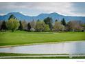 Scenic view of a lush green golf course with a tranquil pond and majestic mountains in the distance at 7034 Indian Peaks Trl, Boulder, CO 80301