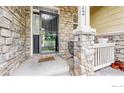 Inviting front porch with stone pillars and a secure screen door, enhanced by potted plants and a seating area at 1872 W 130Th Dr, Westminster, CO 80234