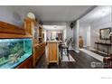 Open-concept living space featuring wood floors, a large aquarium, and a bar with seating, ideal for entertaining at 1872 W 130Th Dr, Westminster, CO 80234