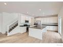 Bright and airy kitchen featuring white cabinets, stainless steel appliances, and a center island at 189 Baler Ct, Brighton, CO 80601