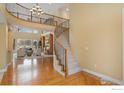 Grand foyer with a curved staircase, wood floors, and a view into the formal living room at 1949 Wasach Dr, Longmont, CO 80504
