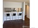 Bright kitchen features a breakfast bar with three stools, complemented by sleek, dark hardwood floors at 2707 Valmont Rd # 111A, Boulder, CO 80304