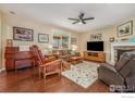 Cozy living room with a stone fireplace, hardwood floors, and natural light streaming through the windows at 4679 Lakeside Dr, Longmont, CO 80504