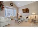 Bright living room featuring vaulted ceiling, white sofas, and elegant glass coffee table at 630 S Snowmass Cir, Superior, CO 80027