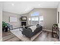 Cozy living room with a fireplace, vaulted ceiling, large windows, and modern decor at 6981 Buckskin Dr, Littleton, CO 80125