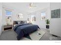 Bright main bedroom with a blue bed, multiple windows, and a decorative rug at 12364 Hayloft Ln, Thornton, CO 80241