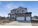 Two-story home with gray siding, stone accents, a three-car garage, and a charming covered front porch at 1836 Westport Ave, Berthoud, CO 80513