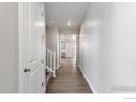 Inviting hallway showcasing light gray walls, wood-look floors, and doors leading to various rooms throughout the house at 1866 Sawtooth Mountain Dr, Berthoud, CO 80513