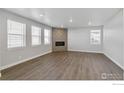 Bright living room featuring a stone fireplace, neutral walls, and sizable windows that fill the space with natural light at 1866 Sawtooth Mountain Dr, Berthoud, CO 80513