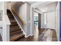 Welcoming entryway featuring hardwood floors and staircase with wooden handrail at 244 Pipit Lake Way, Erie, CO 80516