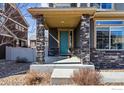 Inviting front porch featuring stone columns and a bright teal door at 244 Pipit Lake Way, Erie, CO 80516