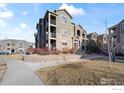 Exterior view of a multi-Gathering building showcasing balconies, stone accents, and surrounding landscaping at 2800 Blue Sky Cir # 208, Erie, CO 80516