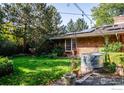 Expansive backyard with lush green lawn, mature trees, garden features and solar panels on brick home at 390 Inca Pkwy, Boulder, CO 80303