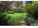 Lush backyard featuring a vast lawn surrounded by mature trees and diverse greenery, creating a private retreat at 390 Inca Pkwy, Boulder, CO 80303