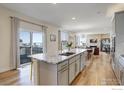 Open-concept kitchen with granite island, modern appliances, and hardwood floors at 55 Morgan S Cir, Erie, CO 80516