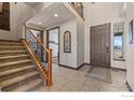 Inviting foyer with staircase, tile flooring, and natural light through a window at 6006 E 162Nd Pl, Brighton, CO 80602