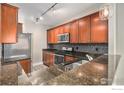 Kitchen with stainless steel appliances, dark granite countertops, and wood cabinetry at 9039 E Panorama Cir # 201, Englewood, CO 80112
