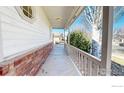 Covered front porch featuring brick accents and a view of the front yard and street at 1121 Jefferson Dr, Berthoud, CO 80513