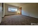 Bright living room with a large window and neutral carpet, offering a cozy and inviting atmosphere at 117 Valentine Ln, Longmont, CO 80501