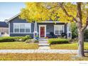 Charming curb appeal with manicured lawn, mature tree, and a cozy front porch at 1403 Bluemoon Dr, Longmont, CO 80504