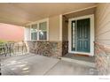 Inviting covered front porch with stone accents and a welcoming entrance door at 15453 E 109Th Ave, Commerce City, CO 80022