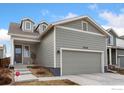 Charming two-story home with gray siding, dormer windows and a two-car garage, with landscaping in the front yard at 2719 Tallgrass Ln, Berthoud, CO 80513