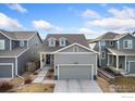 Charming two-story home with gray siding, dormer windows and a two-car garage, with landscaping in the front yard at 2719 Tallgrass Ln, Berthoud, CO 80513