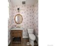 Charming powder room with floral wallpaper, a wooden vanity, and a round mirror at 3182 5Th St, Boulder, CO 80304