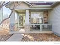 Inviting front porch featuring stone pillars, a cozy seating area, and a well-manicured garden at 4007 Sandcherry Pl, Longmont, CO 80503