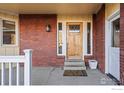 Covered front porch featuring a brick facade, decorative front door, and cozy entryway at 5266 Gallatin Pl, Boulder, CO 80303