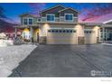 Charming two-story home featuring a three car garage, set against a twilight sky at 5482 Wetlands Dr, Frederick, CO 80504