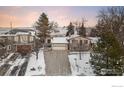 Aerial view of a home with a large driveway and garage, nestled among trees and snow-covered ground at 5564 Colt Dr, Longmont, CO 80503