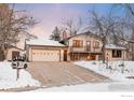 View of the home with a two-car garage and inviting entrance in a winter setting at 5564 Colt Dr, Longmont, CO 80503