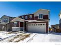 Two-story home featuring a two-car garage, stone accents, and a well-maintained front yard with snowy landscaping at 6121 Easton Cir, Frederick, CO 80504