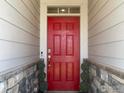 Charming red front door flanked by decorative shrubbery and stone accents, creating a warm welcome at 1431 Vantage Pkwy, Berthoud, CO 80513