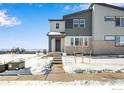 Modern home with gray siding and brick accents, surrounded by a snowy landscape at 1525 E 3Rd Ave, Longmont, CO 80501