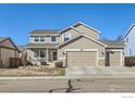 Inviting two-story home with a covered front porch and a three car garage with tasteful stone accents at 1931 Rannoch Dr, Longmont, CO 80504