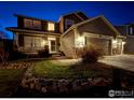 Beautiful two-story home with a covered front porch and a three car garage lit for an evening welcome at 1931 Rannoch Dr, Longmont, CO 80504