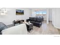 Bright living room with a mounted TV, black leather couch, and view to dining area at 2225 Buchtel Blvd # 703, Denver, CO 80210