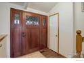 Elegant entryway showcases a beautiful wooden front door with glass panels, complemented by a white interior door at 3549 Columbia Dr, Longmont, CO 80503